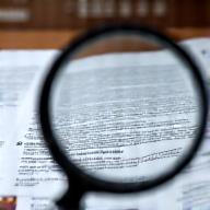 Magnifying glass over a document, symbolizing initial agreement analysis.