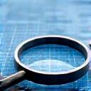 Magnifying glass over a business plan, symbolizing detailed business objectives assessment.